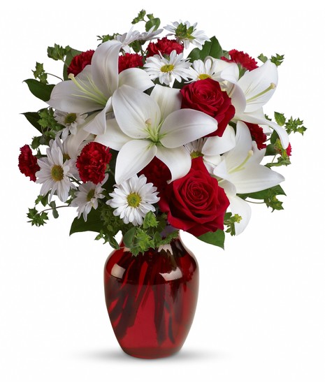 Red roses, snow white lilies and playful daisies are gathered in a ruby red vase